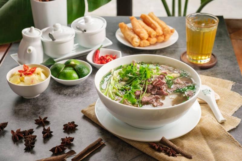 Một tô bún trộn thịt nướng đầy đặn hấp dẫn với đầy đủ các thành phần: bún, thịt nướng, rau sống, chả giò, nước chấm.